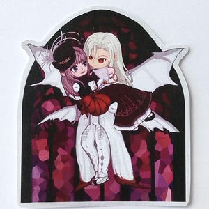 May include: A sticker featuring an anime-style illustration of two figures. One figure, with white hair and red eyes, holds another figure with pink hair and a black hat. The background is a stained-glass design with shades of red and purple.