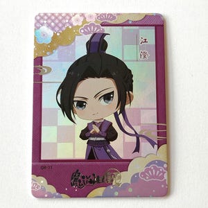 Puede incluir: Una tarjeta rectangular con un personaje de anime de estilo chibi con cabello negro y atuendo púrpura. La tarjeta tiene un borde púrpura con diseños florales y de nubes. El personaje está en una pose con las manos juntas. La tarjeta tiene texto japonés.