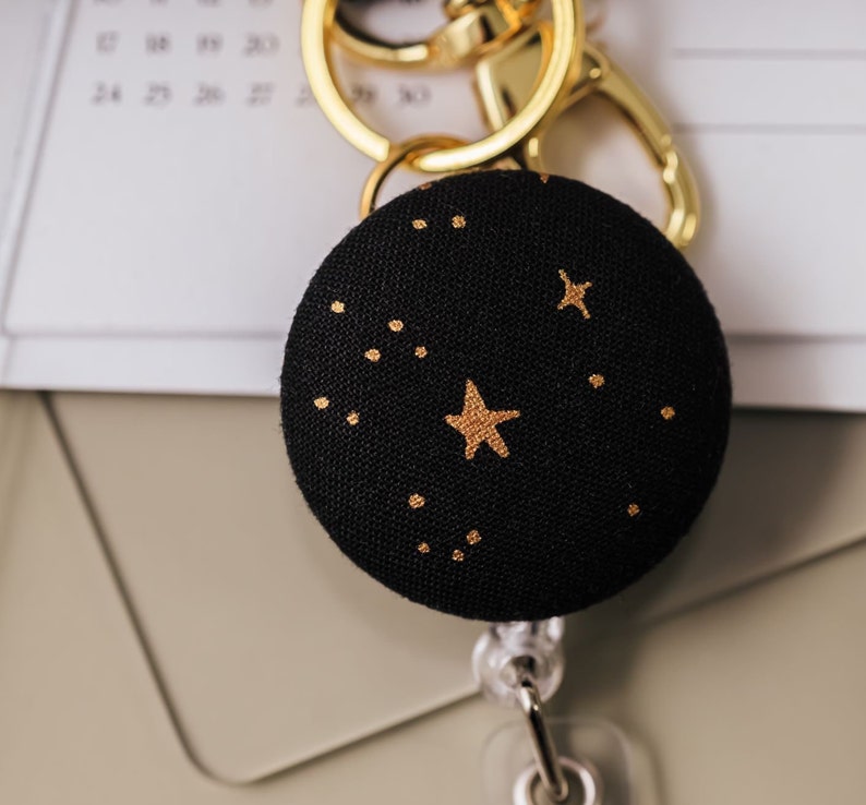 Badge reel made from black fabric with a metallic gold star print.