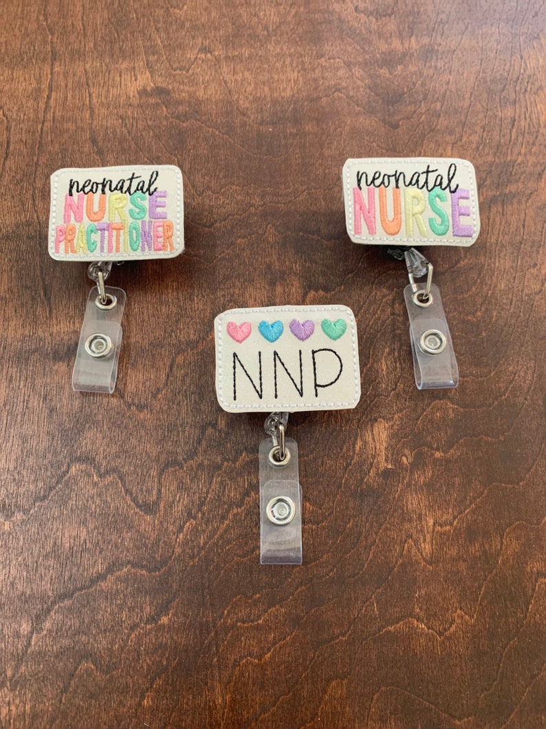 May include: Three white badge reels with colorful embroidered text. The top two reels say "neonatal nurse" and the bottom reel says "NNP" with four small hearts.