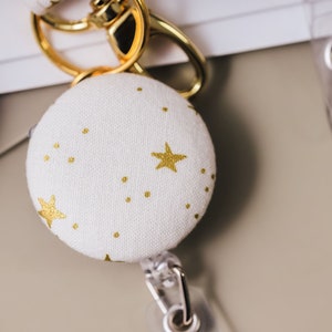 Badge reel made from a white cotton fabric with metallic gold stars.