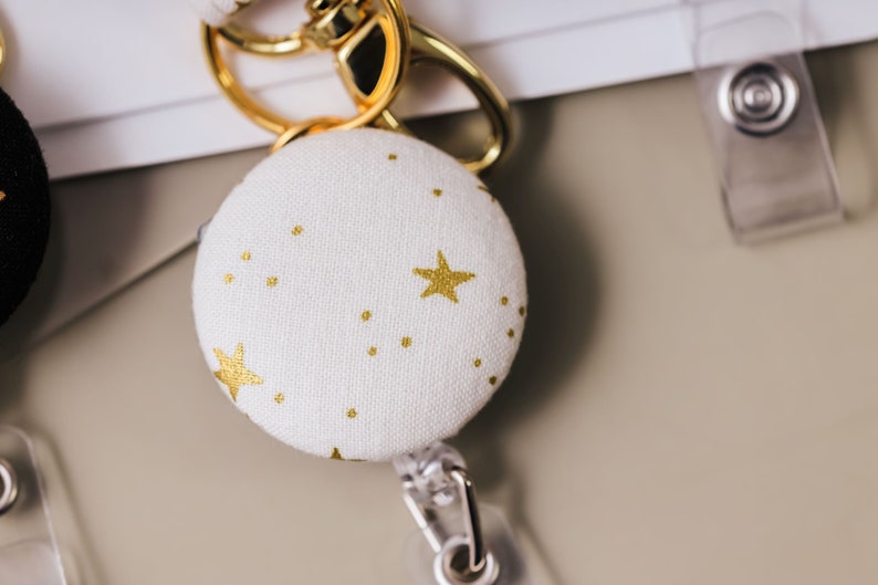 Badge reel made from a white cotton fabric with metallic gold stars.
