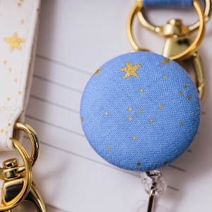 Badge reel made from a blue fabric with metallic gold stars attached to a lanyard.