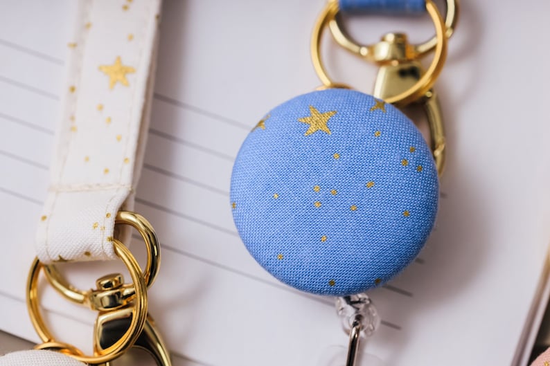 Badge reel made from a blue fabric with metallic gold stars attached to a lanyard.