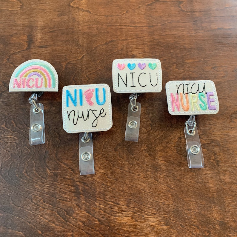 May include: Four embroidered badge reels with the text "NICU" and "NICU Nurse". The reels feature various designs, including a rainbow, hearts, and baby feet. Each reel has a clear plastic strap and a metal clip.
