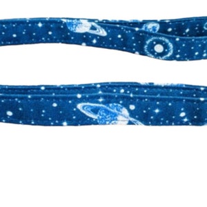 May include: A blue fabric leash with a white galaxy print featuring stars, planets, and moons.