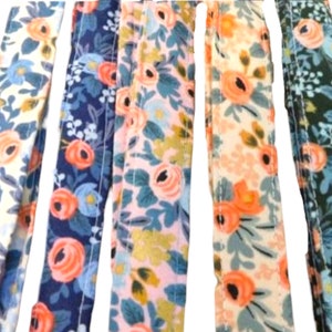 May include: Five fabric strips with a floral pattern. The strips are in different colors, including white, blue, pink, and green. The floral pattern features pink flowers and green leaves.