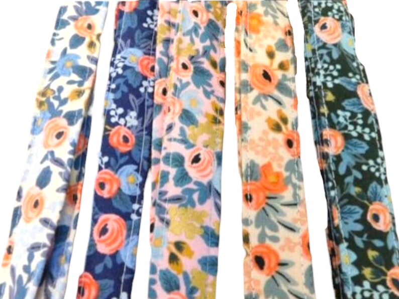 May include: Five fabric strips with a floral pattern. The strips are in different colors, including white, blue, pink, and green. The floral pattern features pink flowers and green leaves.