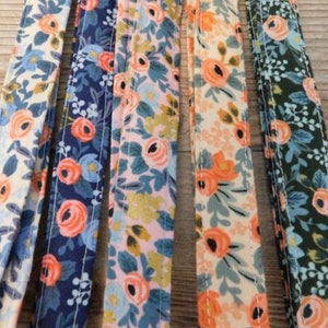 May include: Five different fabric strips with floral patterns. The strips are in shades of blue, pink, green, and white with orange flowers.