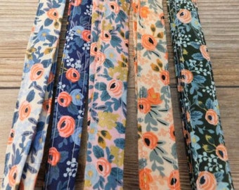 May include: Five different fabric strips with floral patterns. The strips are in shades of blue, pink, green, and white with orange flowers.