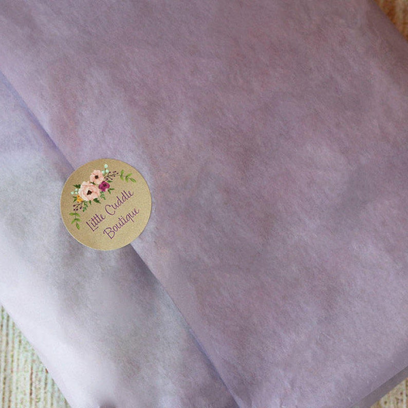 Puede incluir: Una pegatina redonda marr&oacute;n con un dise&ntilde;o floral y el texto "Little Cuddle Boutique" en blanco.