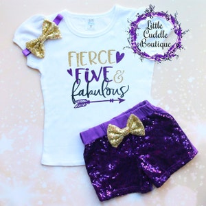 May include: A white t-shirt with purple glitter text that says "Fierce Five & Fabulous" with a purple arrow pointing to the right. The shirt is paired with purple sequined shorts with a gold bow.