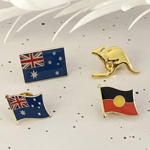 May include: Four enamel pins featuring Australian themes. The pins are gold-toned and feature a kangaroo, the Australian flag, and the Aboriginal flag.