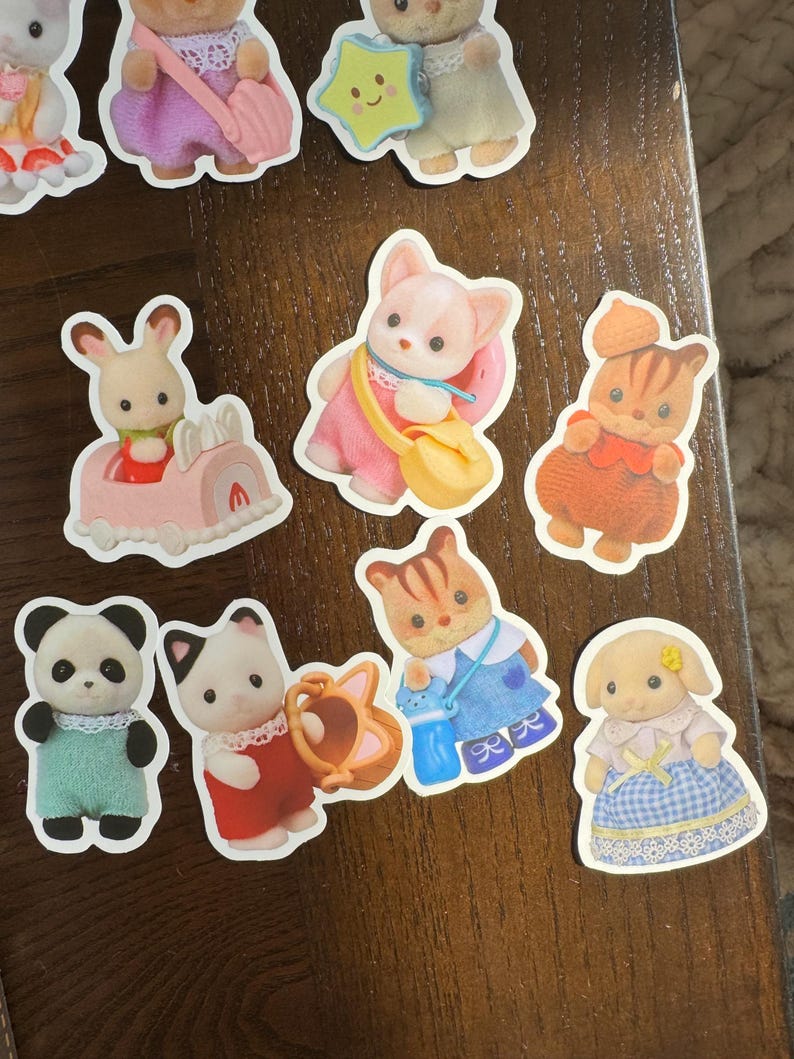 May include: A selection of colourful stickers depicting animal characters in outfits. The stickers include a panda, a cat with a watering can, a rabbit in a car, and other animal figures. The stickers have a white border.