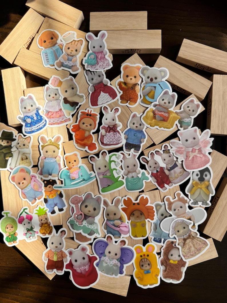 May include: A selection of colourful stickers featuring animal characters in detailed outfits. The stickers include bears, bunnies, cats, and other animals dressed in costumes and clothing. The stickers are scattered on a wooden surface.