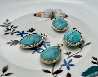 May include: Four turquoise gemstone pendants with gold settings. The gemstones are oval and teardrop shaped.
