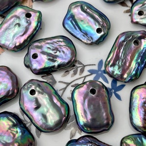 May include: A collection of iridescent black baroque pearl beads with a hole drilled through each one. The pearls are irregularly shaped and have a smooth, glossy finish.