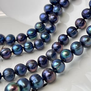 May include: A strand of dark blue iridescent pearls, strung on a black cord. The pearls are round and smooth, with a slight sheen.