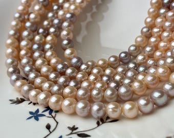 May include: A strand of pearls in shades of pink, lavender, and white. The pearls are round and smooth, and they are strung together on a clear thread.