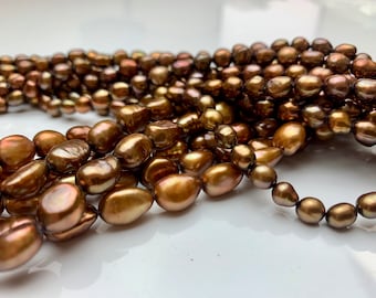 May include: A strand of brown baroque pearls. The pearls are irregular in shape and have a lustrous sheen.