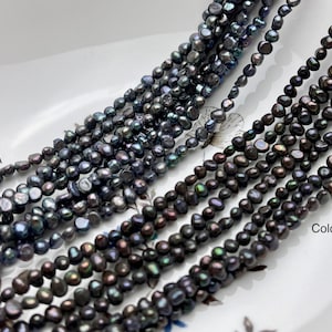 Può includere: Due fili di perle d'acqua dolce nere, uno con una lucentezza più iridescente dell'altro, etichettati "Colore A" e "Colore B".