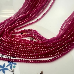 Peut inclure: Un brin de perles de pierres précieuses facettées rouge foncé. Les perles sont petites et uniformes en taille et en forme. Les perles sont enfilées sur un fil transparent et sont prêtes à être utilisées pour la fabrication de bijoux.