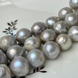 May include: A strand of large, iridescent, grey pearls. The pearls are round and have a smooth, glossy finish.