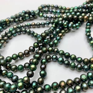 May include: A strand of dark green freshwater pearls. The pearls are round and have a slight iridescent sheen.