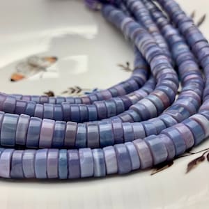 May include: A strand of purple and white shell beads. The beads are round and have a slightly iridescent finish.
