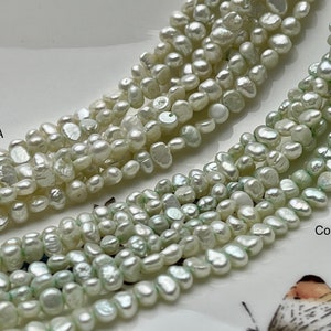 May include: Two strands of white freshwater pearls, one strand is a creamy white and the other strand is a pale green. The strands are labeled "Color A" and "Color B".