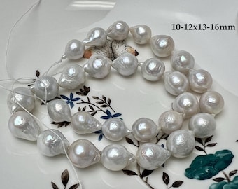 May include: A strand of white baroque pearls with an iridescent luster, strung on a thin white thread. The pearls have irregular, organic shapes and sizes ranging from 10-12x13-16mm as indicated by the text printed on the surface.