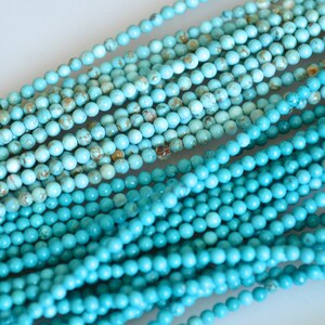Peut inclure: Gros plan sur plusieurs brins de petites perles rondes turquoise. Les perles sont de couleur bleu clair avec des mouchetures marron et beige. Les perles sont enfilées, créant un aspect texturé. Idéal pour la fabrication de bijoux ou les projets d'artisanat.