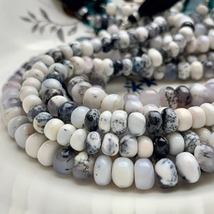 May include: A strand of white and black opal beads. The beads are round and have a smooth, polished finish. The beads are strung on a white cord.