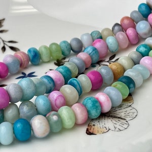 May include: A strand of colorful gemstone beads in shades of blue, green, and pink. The beads are round and have a smooth, polished finish.