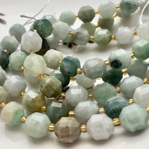 May include: A strand of faceted jade beads in shades of green and white with gold accents. The beads are strung on a white cord.