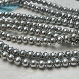 May include: A strand of silver-colored round beads. The beads are smooth and shiny.