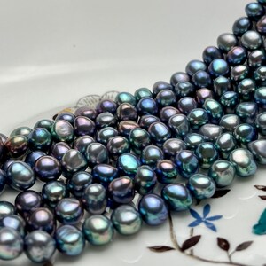 May include: A strand of dark blue freshwater pearls with iridescent hues. The pearls are irregularly shaped and have a smooth, glossy finish.