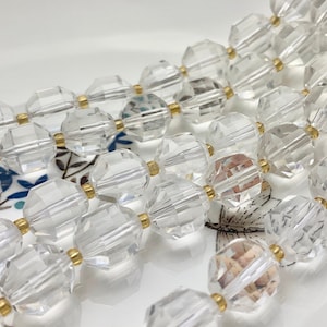 May include: A strand of clear faceted glass beads with gold spacers. The beads are strung on a clear thread and are arranged in a staggered pattern.