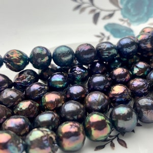 May include: A strand of black pearls with iridescent hues. The pearls are round and smooth, and they are arranged in a loose, flowing pattern.