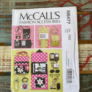 May include: A McCall's Fashion Accessories sewing pattern, M6477, featuring various bag designs. The bags include floral, polka dot, and patterned styles. Accessories like glasses, phones, and a camera are also shown.