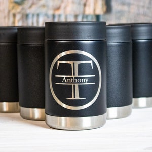 May include: Five black stainless steel insulated beverage holders. One holder has a silver circle with the letter "T" and the name "Anthony" engraved on it.