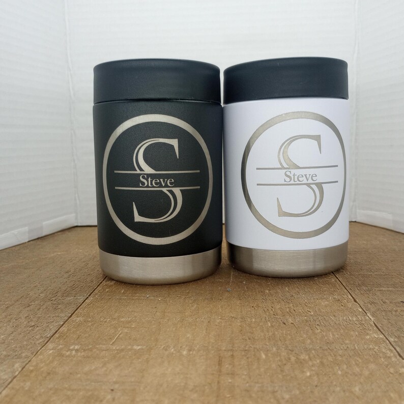 May include: Two stainless steel can coolers with a black and white finish. The coolers have a personalised design with the letter "S" and the name "Steve" engraved on them.