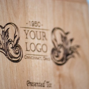 May include: A wooden cutting board with a burnt-in design featuring a stylized floral motif and the text "YOUR LOGO - 1950 - CINCINNATI, OHIO - Presented To".
