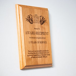 May include: A wooden plaque with an engraved message recognizing an award recipient for 15 years of service. The plaque features a company logo and the text "-1980- YOUR LOGO -PT- Presented To: AWARD RECIPIENT For dedication and quality work over 15 YEARS OF SERVICE Thank you for your daily efforts and dedication, the driving force for the continued success of our organization is people like you. Your passion, loyalty, and talents are invaluable. Thank you."