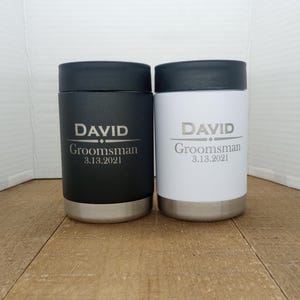 May include: Two stainless steel beverage coolers with black and white lids. The black cooler has the text "DAVID  Groomsman 3.13.2021" and the white cooler has the text "DAVID Groomsman 3.13.2021".