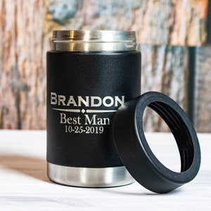 May include: Black insulated can cooler with a silver lid and a black rubber ring. The cooler is engraved with the text "BRANDON Best Man 10-25-2019".