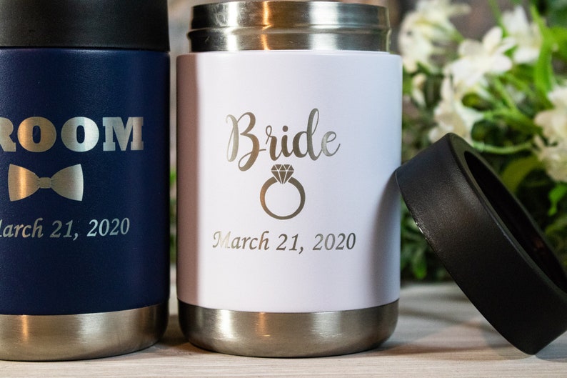 Pu&ograve; includere: Due portabevande in acciaio inox con incisioni personalizzate. Il portabevande blu dice "Groom" con un papillon e "March 21, 2020". Il portabevande bianco dice "Bride" con un anello di diamanti e "March 21, 2020".