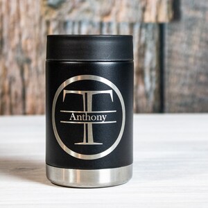 May include: Black insulated can cooler with a silver monogram of the letter "T" and the name "Anthony" engraved on it.