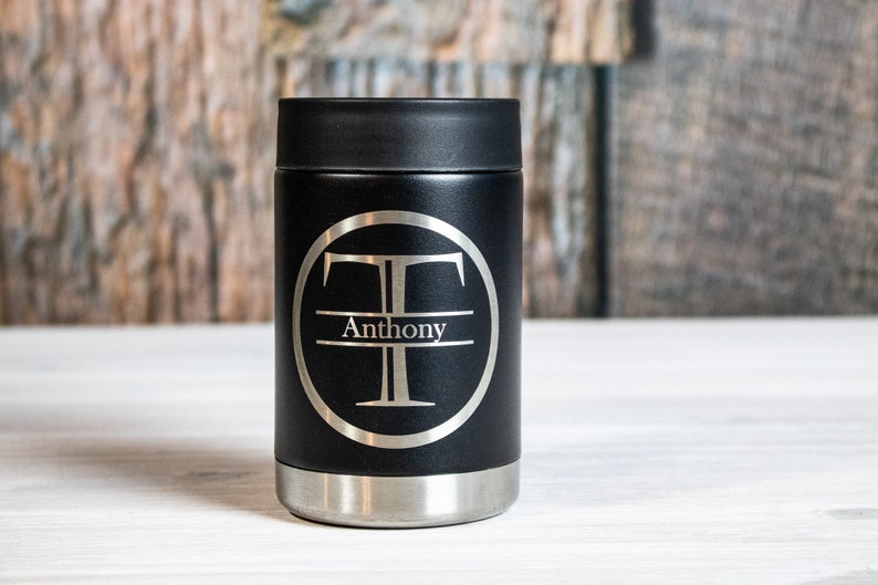 May include: Black insulated can cooler with a silver monogram of the letter "T" and the name "Anthony" engraved on it.