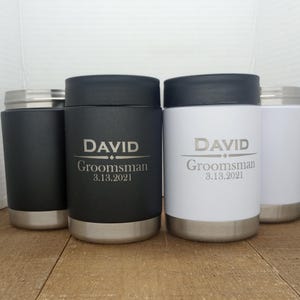 May include: Three stainless steel insulated tumblers with black and white lids. The tumblers are engraved with the name "DAVID" and the text "Groomsman 3.13.2021".